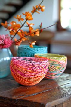 three vases filled with colorful yarn sitting on top of a wooden table