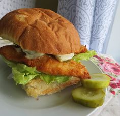 a chicken sandwich with lettuce and pickles on a plate