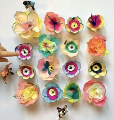 paper flowers are arranged on a white surface and being held by a person's hand