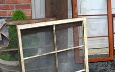 two old windows are sitting outside in front of a garage door, and one is empty