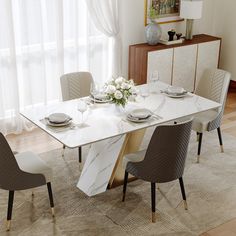 a marble dining table with four chairs and a vase filled with flowers on the side