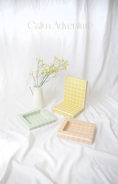 three pieces of furniture sitting on top of a white sheet covered bed next to a vase with flowers in it