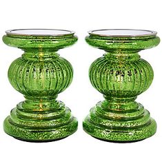 two green glass candlesticks sitting on top of each other in front of a white background