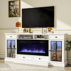 a white entertainment center with an electric fireplace in front of a flat screen tv mounted on the wall