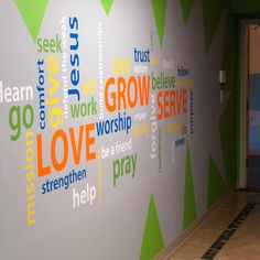 a wall with words written on it in different colors and shapes next to a doorway