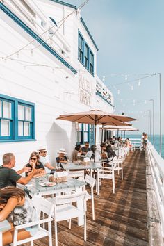 people are sitting at tables on the pier