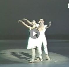 two men in white dance on stage with one holding the other's hand up