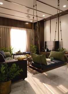 a living room filled with lots of furniture and hanging plants in front of a window