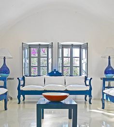 a living room filled with white furniture and blue vases on top of it's tables