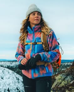 a woman standing on top of a snow covered slope wearing skis and carrying a backpack