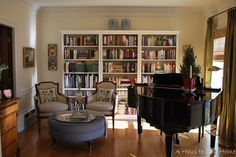 a living room filled with furniture and a piano in front of a bookshelf