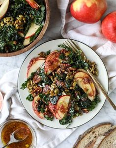 a white plate topped with salad next to sliced apples