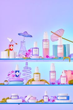 the shelves are filled with different types of skin care products and flowers on display in front of a blue background