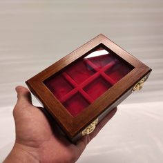 a hand holding a wooden box with red velvet inside