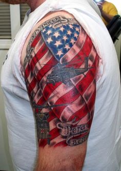 a man's arm with an american flag and cross tattoo on the left shoulder