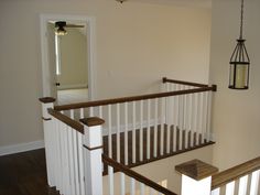 an empty room with white railings and wood handrails in the foreground