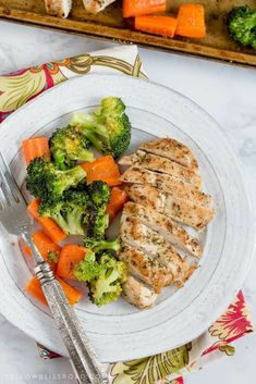 a white plate topped with meat and veggies next to a serving tray filled with broccoli