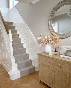 there is a vase with flowers on top of the dresser next to the stair case