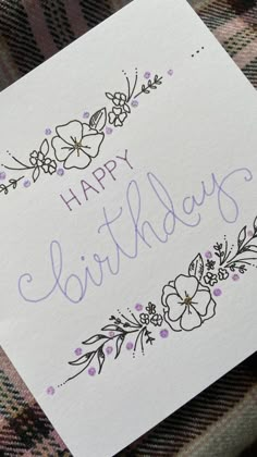 a birthday card with flowers and the words happy birthday written in purple ink on it