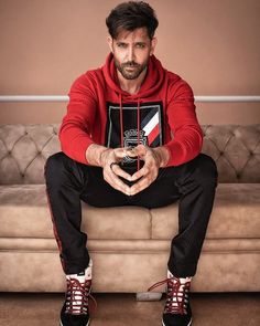 a man sitting on top of a couch with his hands in the shape of a heart