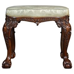 an ornate wooden bench with a white upholstered cushion on the top and bottom