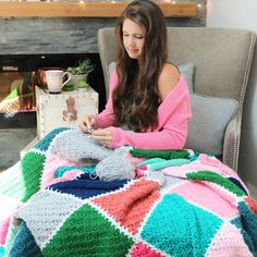 a woman sitting in a chair with a crocheted blanket on top of her