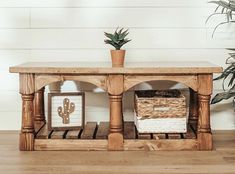 a wooden table with some plants and pictures on it next to a potted plant