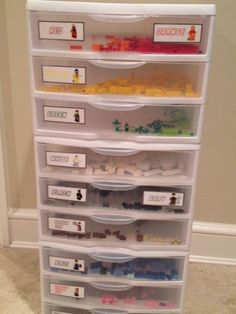 a stack of plastic drawers with legos on the bottom and name tags attached to them