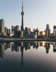 the city skyline is reflected in the still water