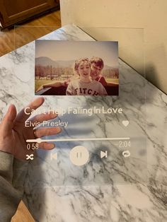 a person holding up a photo on top of a marble table with the words love is falling in love