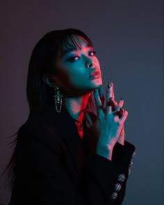 a woman in black shirt holding her hand up to her face with red light shining on her