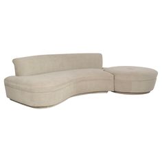 the curved sectional sofa is made out of fabric and has a footstool on one end