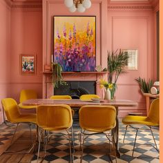 a dining room with pink walls and yellow chairs