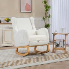 a white rocking chair sitting on top of a wooden floor next to a small table