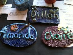 three ceramic plaques sitting on top of a table next to papers and other items with writing