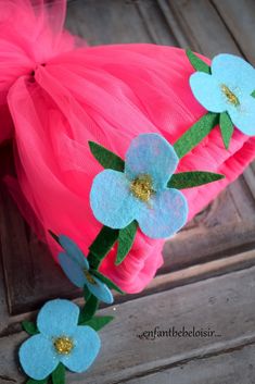 pink tulle dress with blue flowers and green leaves on the bottom, attached to a wooden door