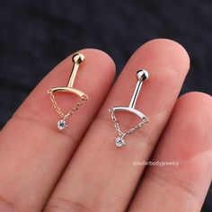 two different types of piercings on someone's finger, one is gold and the other is silver