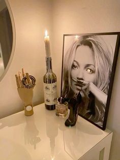 a white table topped with a bottle of wine and a framed photo next to a candle