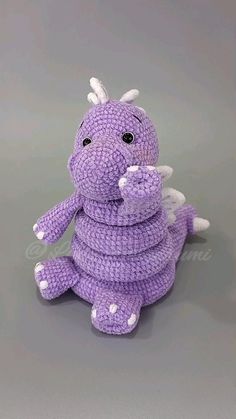 a purple crocheted toy sitting on top of a gray floor next to a stuffed animal