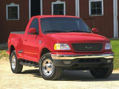 a red pick up truck parked in front of a barn