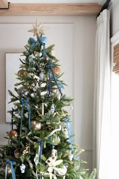 a decorated christmas tree with blue ribbon and ornaments