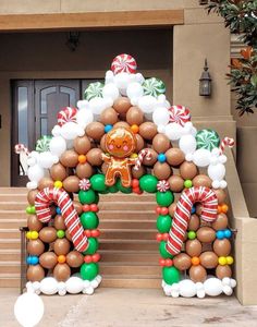 an arch made out of balloons with a gingerbread man in the center and candy canes around it