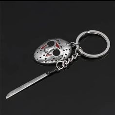 a keychain with a mask on it and a knife sticking out of it