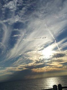 the sun is shining through clouds over the ocean