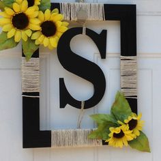 the letter s is decorated with sunflowers and twine on a white wall