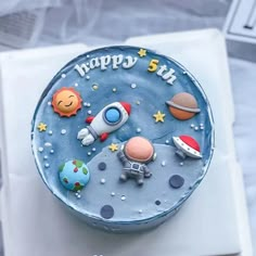 a blue birthday cake with space and stars on it's top is sitting on a white plate