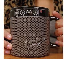 a person holding a coffee mug with the word rock and roll on it's side