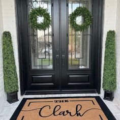 the front door is decorated with wreaths and two black double doors that read, the clark