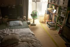 a bedroom with a fan, bookshelf and window