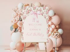 a welcome sign surrounded by balloons, flowers and other decorations in pastel colors on a pink background